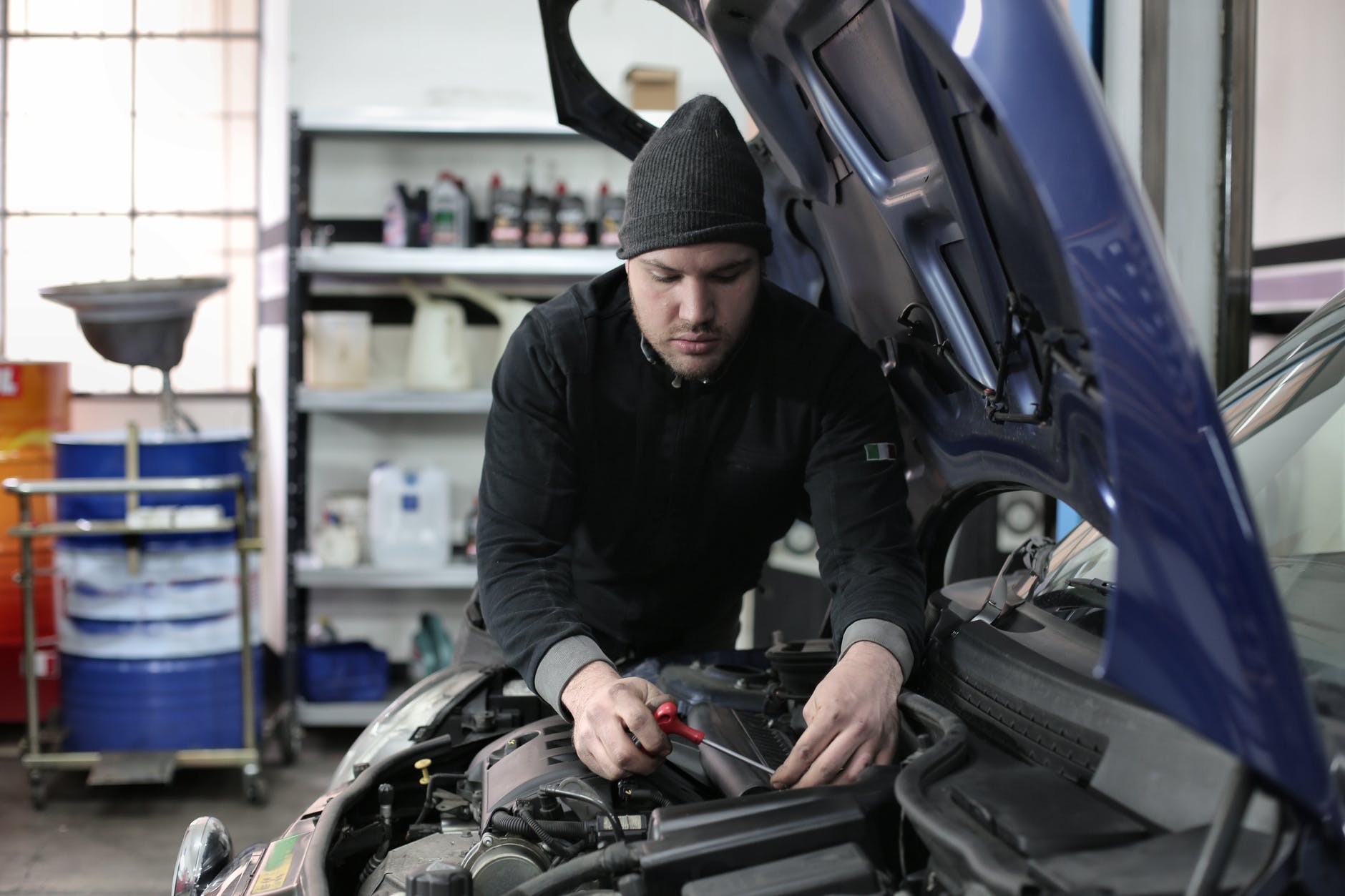 man in black jacket and black knit cap standing near vehicle